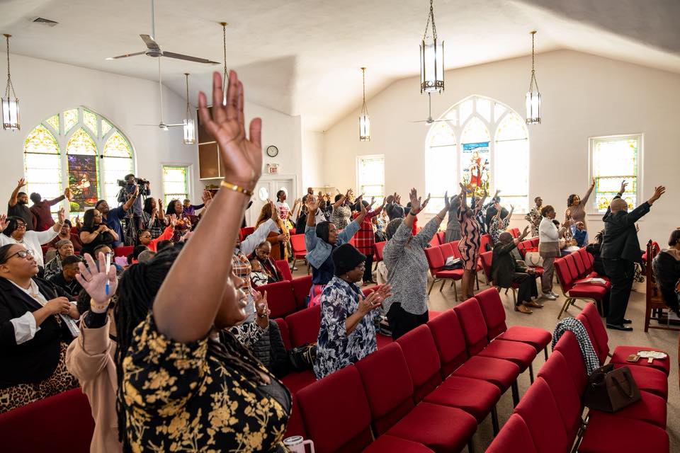 The MarketPlace Movement congregation with hands raised in worship
